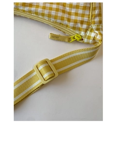 Detail of yellow checkered dumpling bag showing fabric texture and adjustable strap buckle