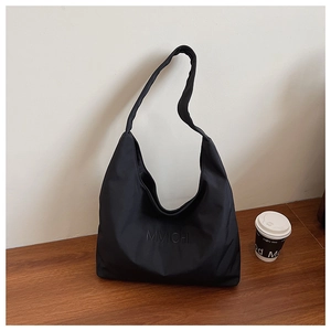 Close-up of black nylon tote bag with embroidered logo on a wooden surface