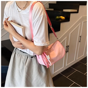 Pink nylon crossbody pillow bag with adjustable wide strap shown in lifestyle setting
