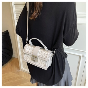 Detailed view of cream crossbody bag with geometric embroidery and metal lock clasp