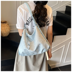 Detail of light blue embroidered tote bag featuring floral texture and drawstring with beads