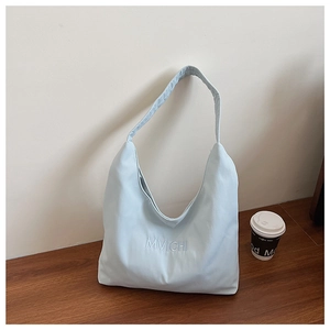 Detail view of the light blue canvas tote bag featuring white MVICHI embroidery and strap
