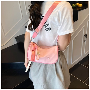 Close-up of pink nylon crossbody bag with embossed logo and wide fabric shoulder strap