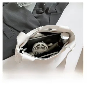 Spacious interior of white faux leather tote bag with tech accessories and daily essentials