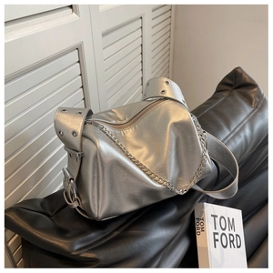 Detail of silver metallic cylinder bag featuring chunky metal buckles and fine chain strap