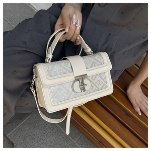 Close-up of beige square handbag with ethnic geometric embroidery and metal buckle