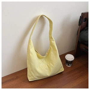 Close-up of embroidered MVICHI logo on light yellow textured fabric tote bag