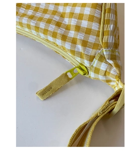 Close-up of yellow gingham fabric bag with a high-quality zipper and detailed stitching