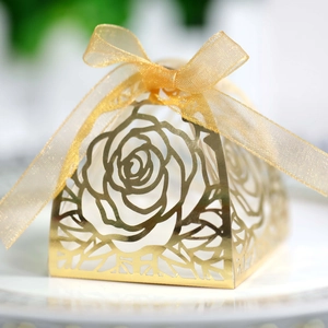 Dettaglio macro della scatola per confetti dorata con intaglio laser e fiocco in seta