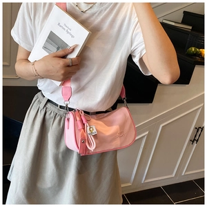 Detailed view of pink crossbody pillow bag with woven charm and embossed logo