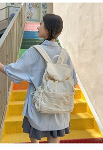 Vue arrière d'une femme portant un sac à dos crème à cordon sur un escalier coloré