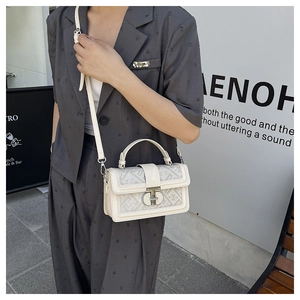 Detail view of cream square bag with geometric texture and silver lock on a street model