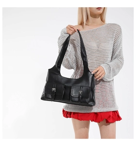Détail d'un sac à bandoulière en cuir noir vintage avec deux poches avant et boucles argentées
