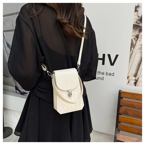 Detail of woven texture and silver twist lock on a beige vertical mini crossbody bag