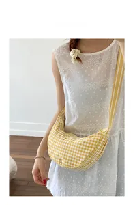 Detail of yellow checkered dumpling bag with matching striped strap on a model
