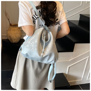 Detail of light blue embossed fabric shoulder bag with floral jacquard texture