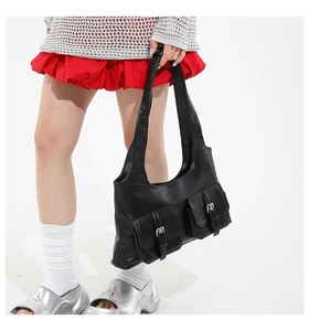 Detail of black faux leather shoulder bag with twin front pockets and silver metal buckles