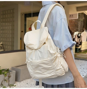 Vue détaillée d'un sac à dos beige à cordon en tissu lavé avec poches latérales