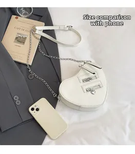 Detailed comparison of white heart-shaped crossbody bag size with a smartphone for scale