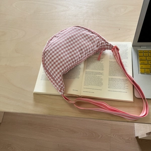 Detail of pink plaid canvas hobo bag on an open book with soft aesthetic lighting