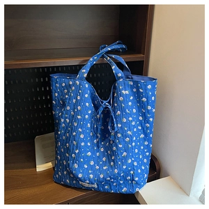 Close-up of blue floral quilted canvas tote bag with tie detail and brand label