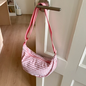 Detailed close-up of pink checkered canvas hobo bag with adjustable striped strap