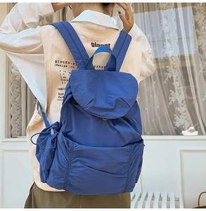 Détail d'un sac à dos bleu en nylon avec cordon et larges bretelles porté au dos
