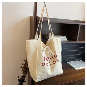 Detail of canvas tote bag with red hello lettering and floral lining on a wooden shelf