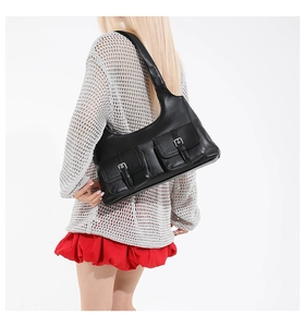 Détail d'un sac hobo noir vintage avec deux poches à rabat et boucles métalliques