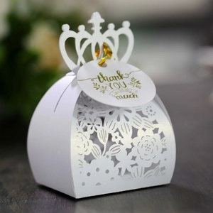 Close-up of pearl white laser-cut hollow candy box with golden ribbon and thank you tag