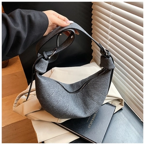 Detail of grey fabric croissant bag with quilted panels and wide shoulder strap