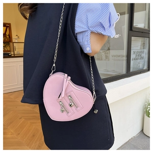 Close-up of pink heart-shaped crossbody bag with gold chain strap and heart zipper detail