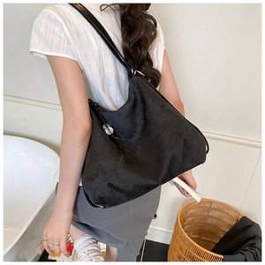 Detail of a large black embroidered hobo bag with subtle textures and silver hardware