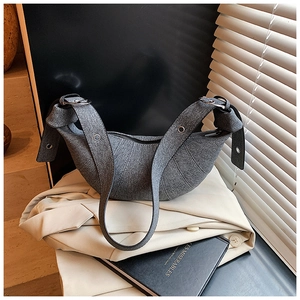 Detail view of the textured canvas dumpling bag showing its wide strap and metal buckle