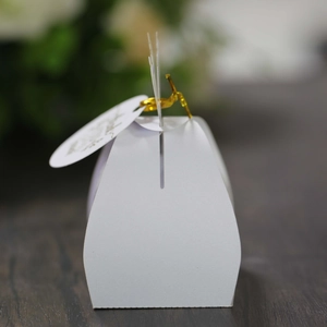Close-up of white gift box with round tag and gold wire tie for wedding favors