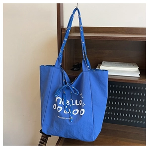 Close-up of a blue canvas tote bag featuring floral straps and a cute decorative bow knot