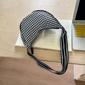 Detail of checkered canvas half-moon crossbody bag with adjustable striped strap and zipper