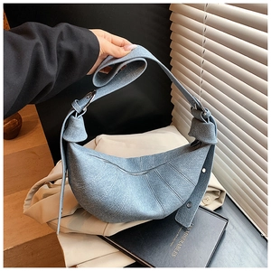 Detail of blue denim crescent bag featuring knotted shoulder strap and silver metal ring