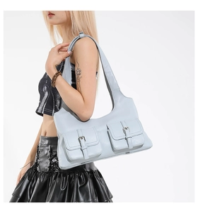 Détail d'un sac porté épaule bleu clair avec deux poches frontales et boucles argentées
