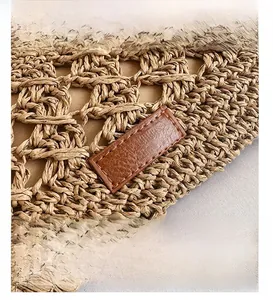 Close-up of woven straw handbag featuring a brown leather patch and neat stitching detail