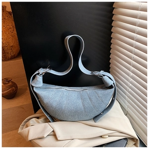 Detailed view of light blue denim croissant bag featuring quilted pleats and silver buckle