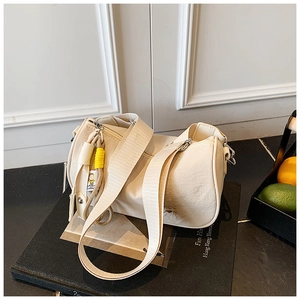 Detail of creamy white cylinder bag featuring pebble leather texture and canvas strap