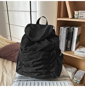 Détail d'un sac à dos noir en nylon avec cordon de serrage et plis sur une valise