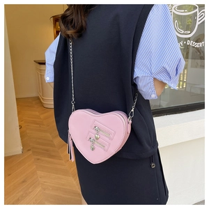 Close-up of a pink heart-shaped crossbody bag with silver chain strap and zipper details