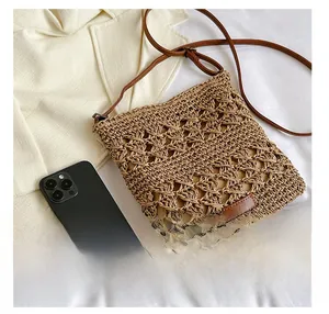 Detail view of woven crossbody bag with hollow lattice pattern and mobile phone for scale