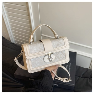 Detailed close-up of woven floral flap with silver twist lock on cream leather bag