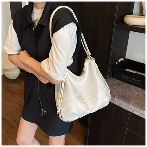Detailed close-up of cream floral jacquard fabric on a large shoulder bag with drawstring