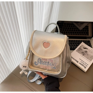 Detail of silver metallic backpack with pink heart embroidery and plush ball charm