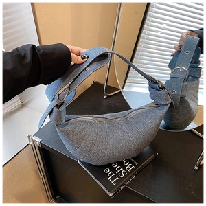 Detailed view of washed denim dumpling bag with quilted pleats and silver metal hardware