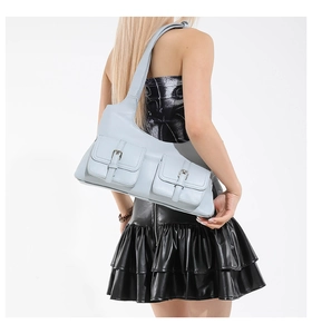 Sac à bandoulière en cuir mat bleu avec deux poches à rabat porté par un mannequin